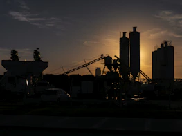 A historic industrial site with old machinery silhouetted against a sunset.