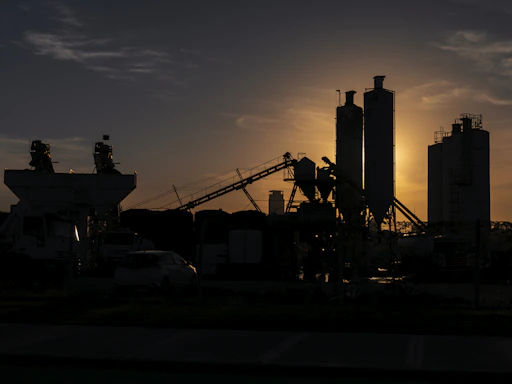 A rugged industrial site at sunset with heavy machinery silhouetted against the sky.