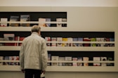 man in white dress shirt standing near white wooden shelf