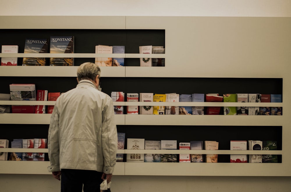 man in white dress shirt standing near white wooden shelf