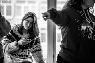 a woman holding a cell phone in front of a window