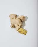 a ginger root and a piece of ginger on a white surface