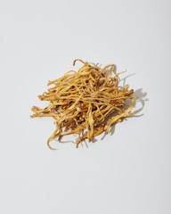 a pile of dried yellow flowers on a white surface