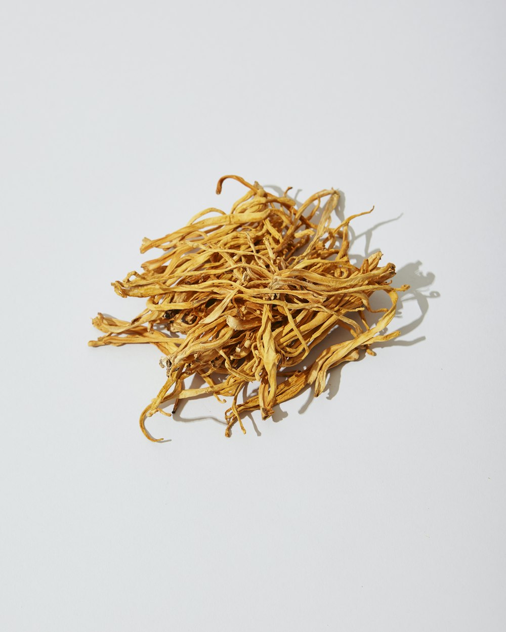 a pile of dried yellow flowers on a white surface