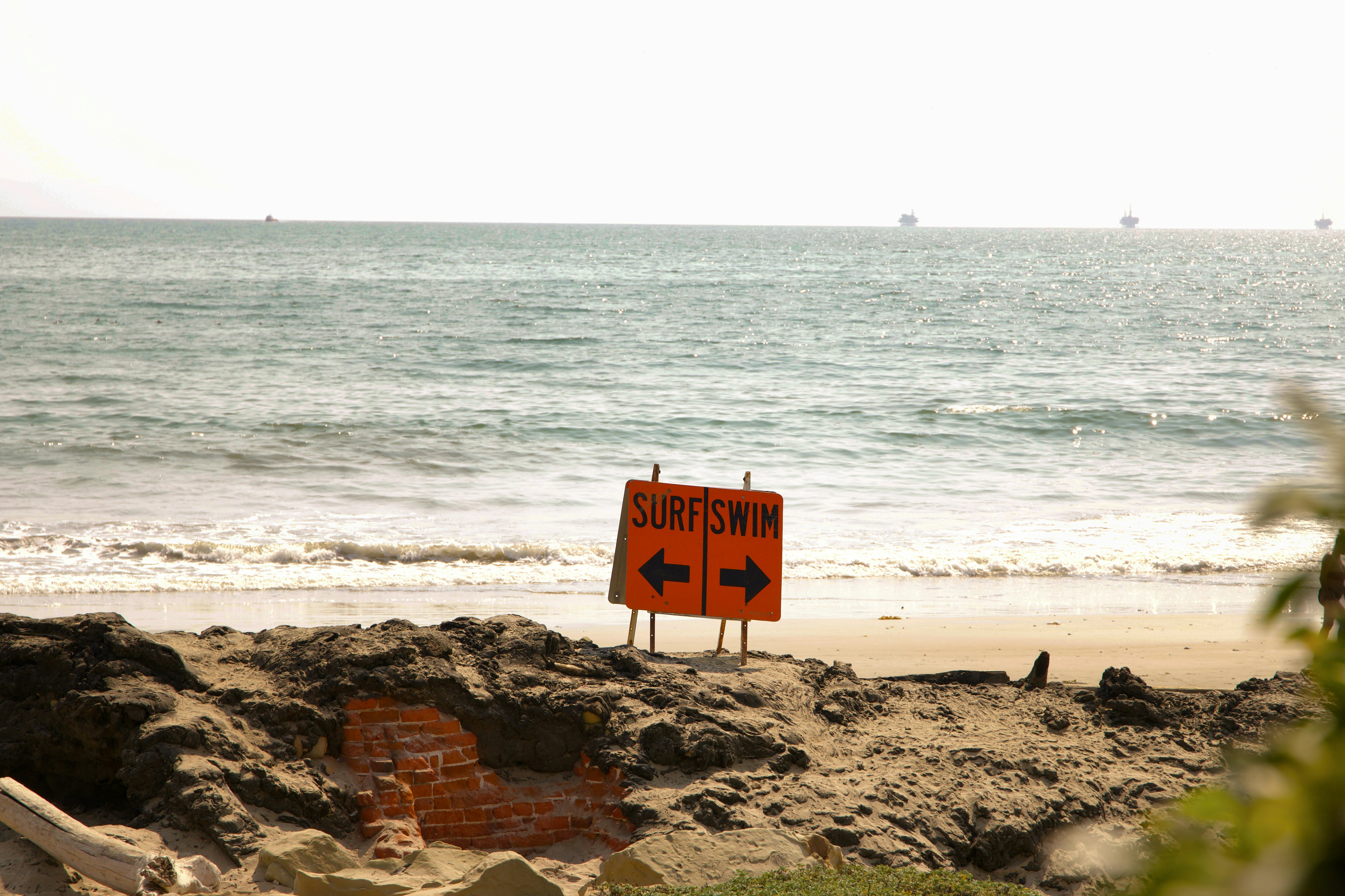white and brown wooden signage on brown rocky shore during daytime