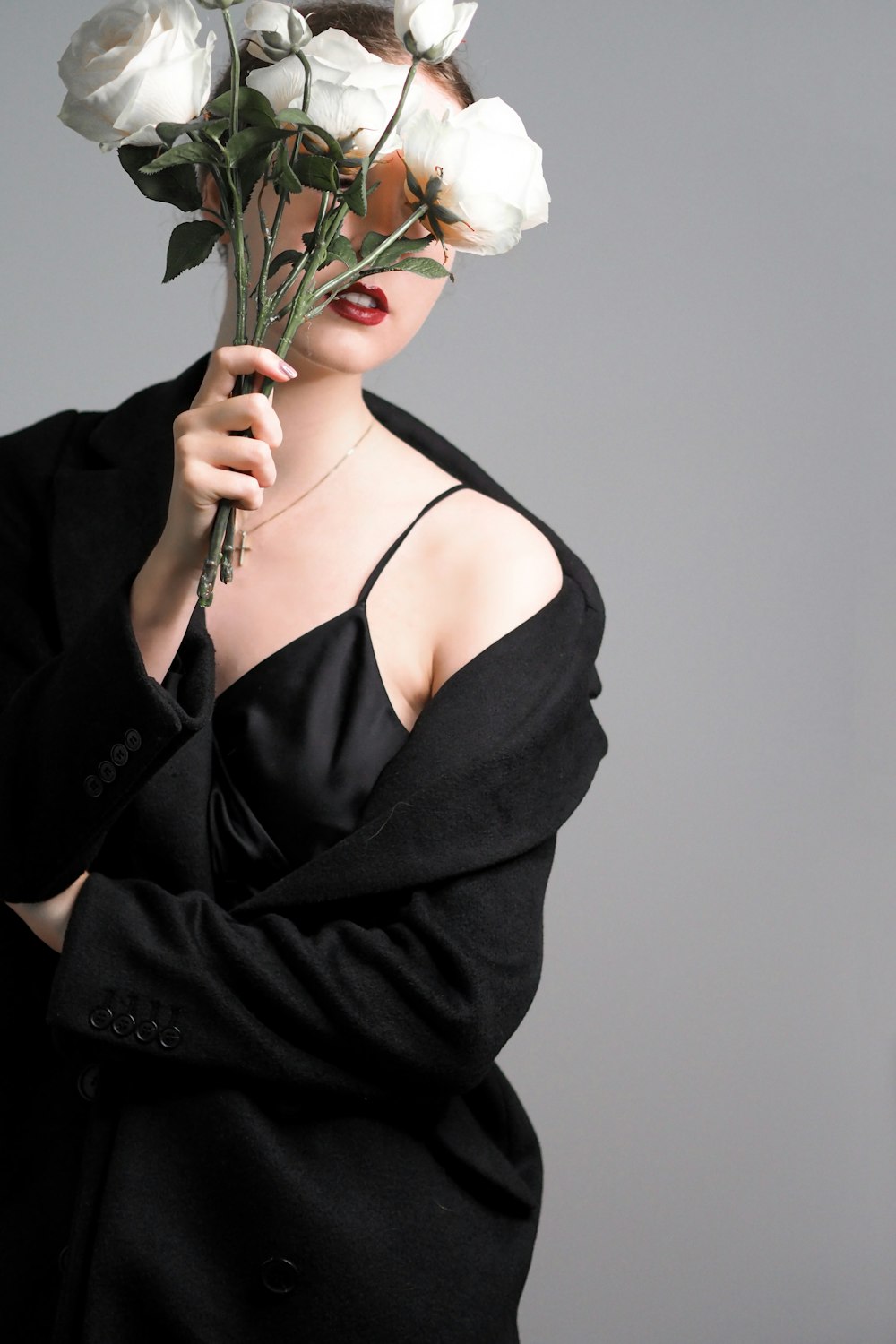 woman in black spaghetti strap top holding white rose