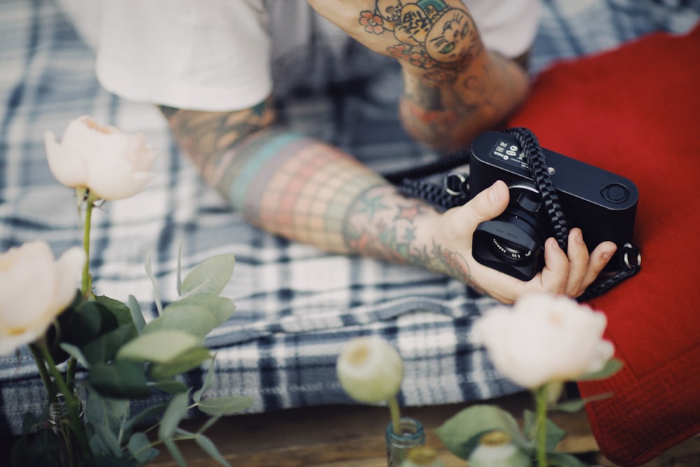 person in white shirt and blue and white plaid pants holding black remote control