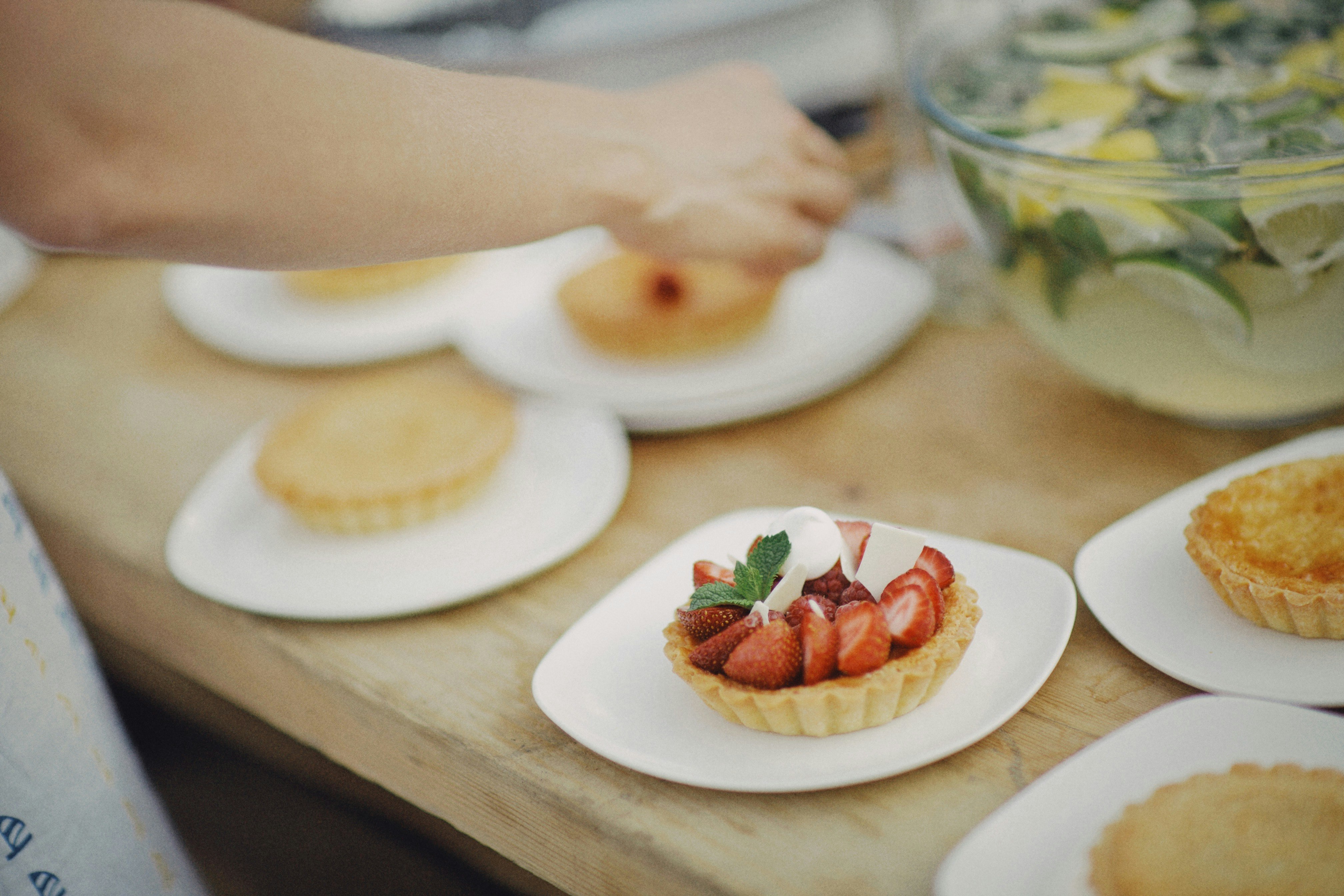 person holding white ceramic plate with sliced strawberry
