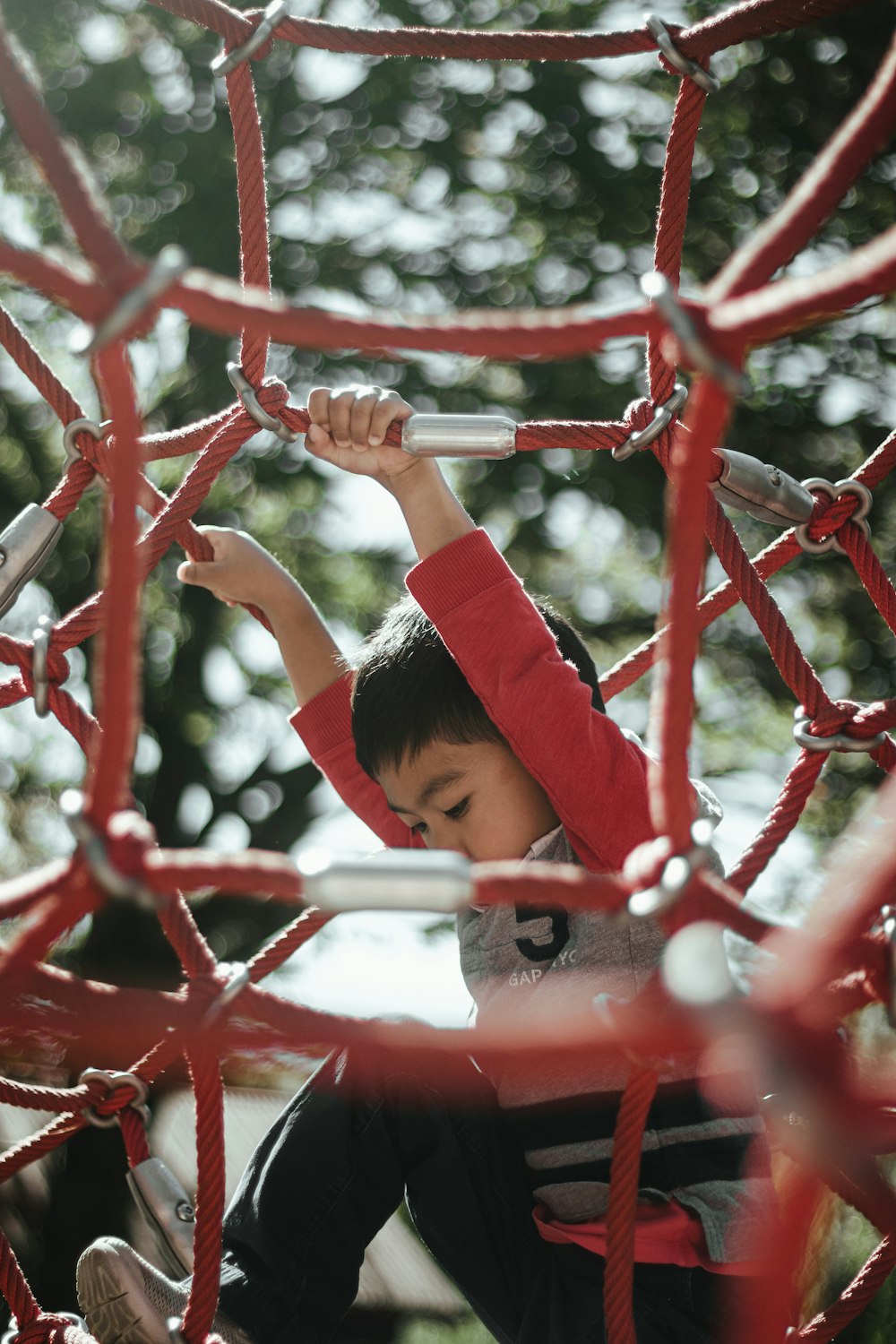 menina na camisa vermelha da manga comprida de pé na cerca de metal vermelha durante o dia