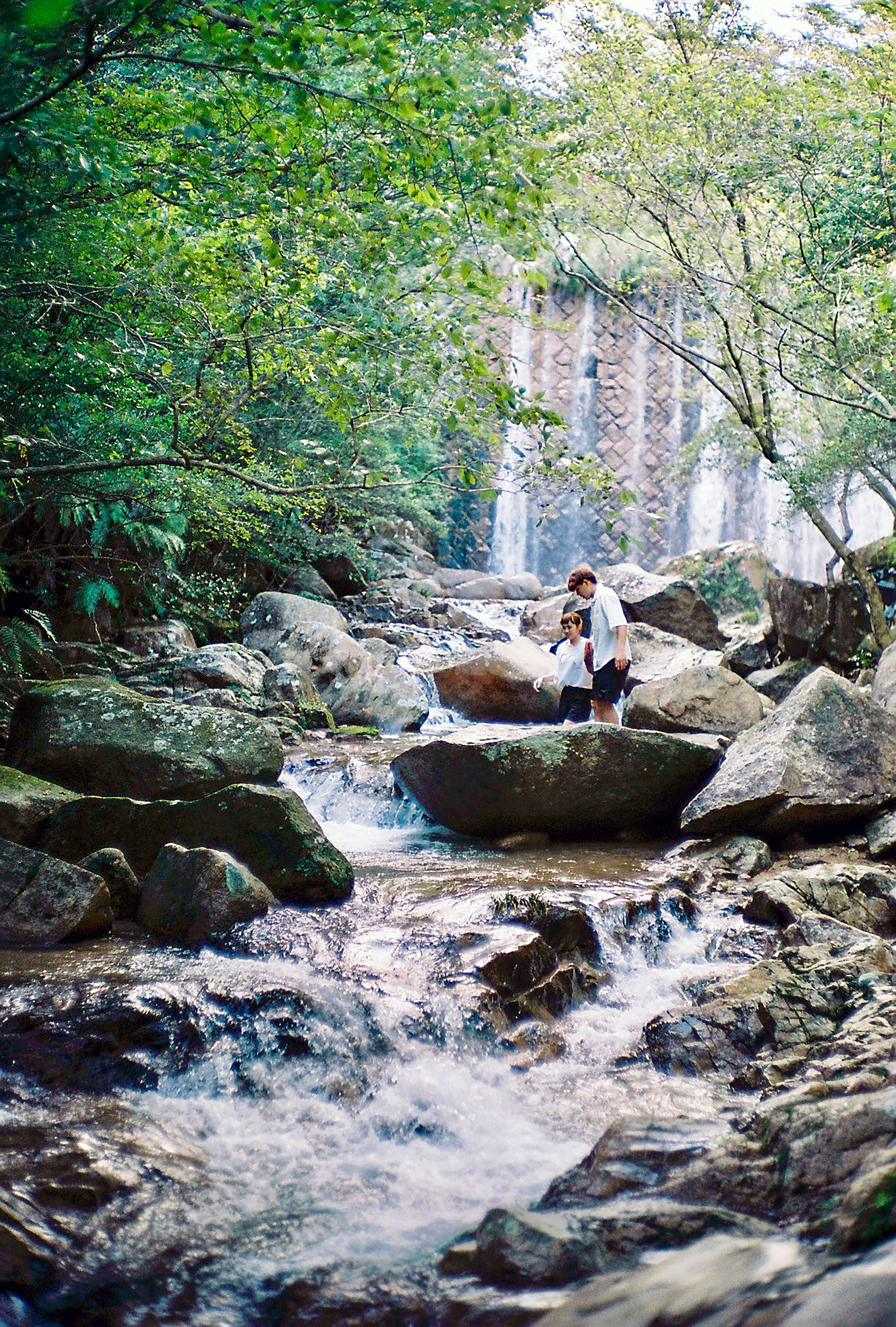 woman in white shirt sitting on rock in river during daytime