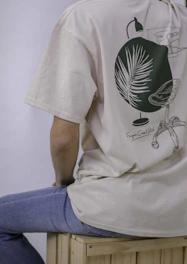 person in white and green crew neck t-shirt and blue denim jeans