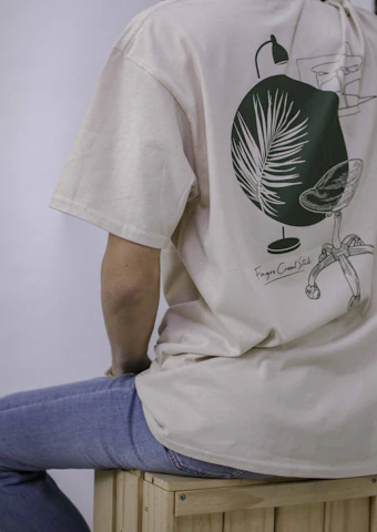 person in white and green crew neck t-shirt and blue denim jeans