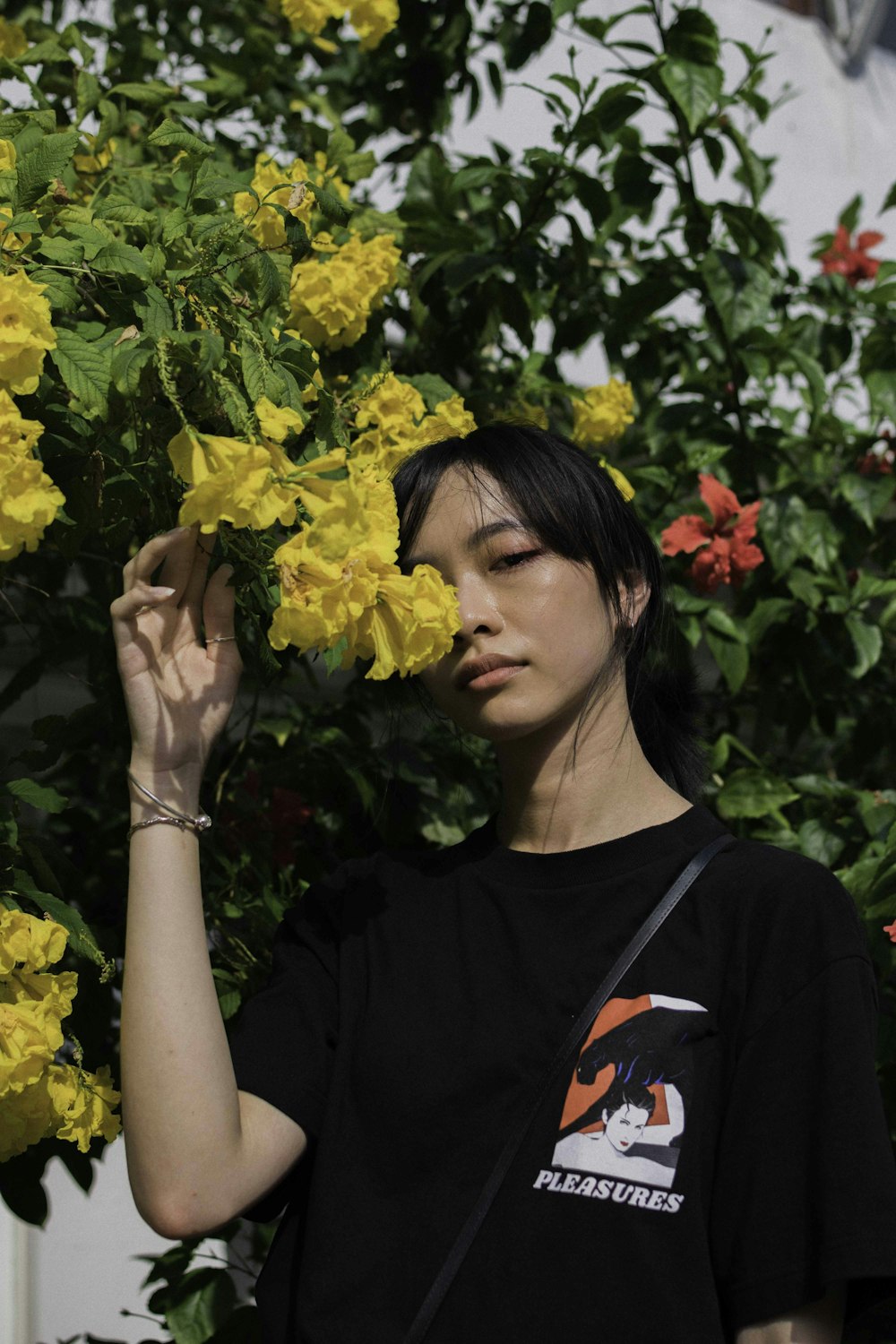 woman in black crew neck shirt holding yellow flower