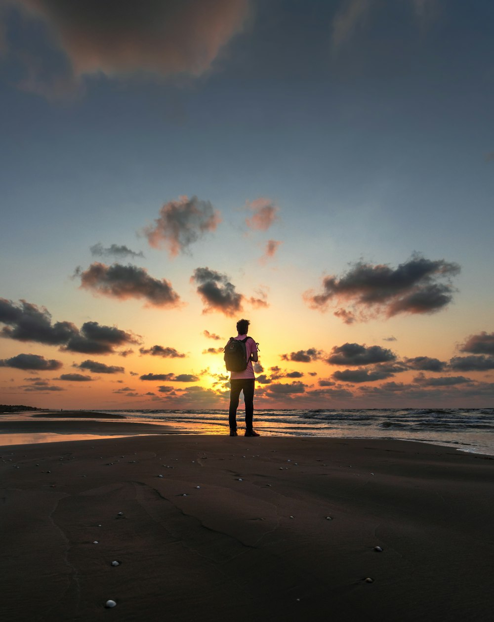 silhouette of person standing on beach during sunset