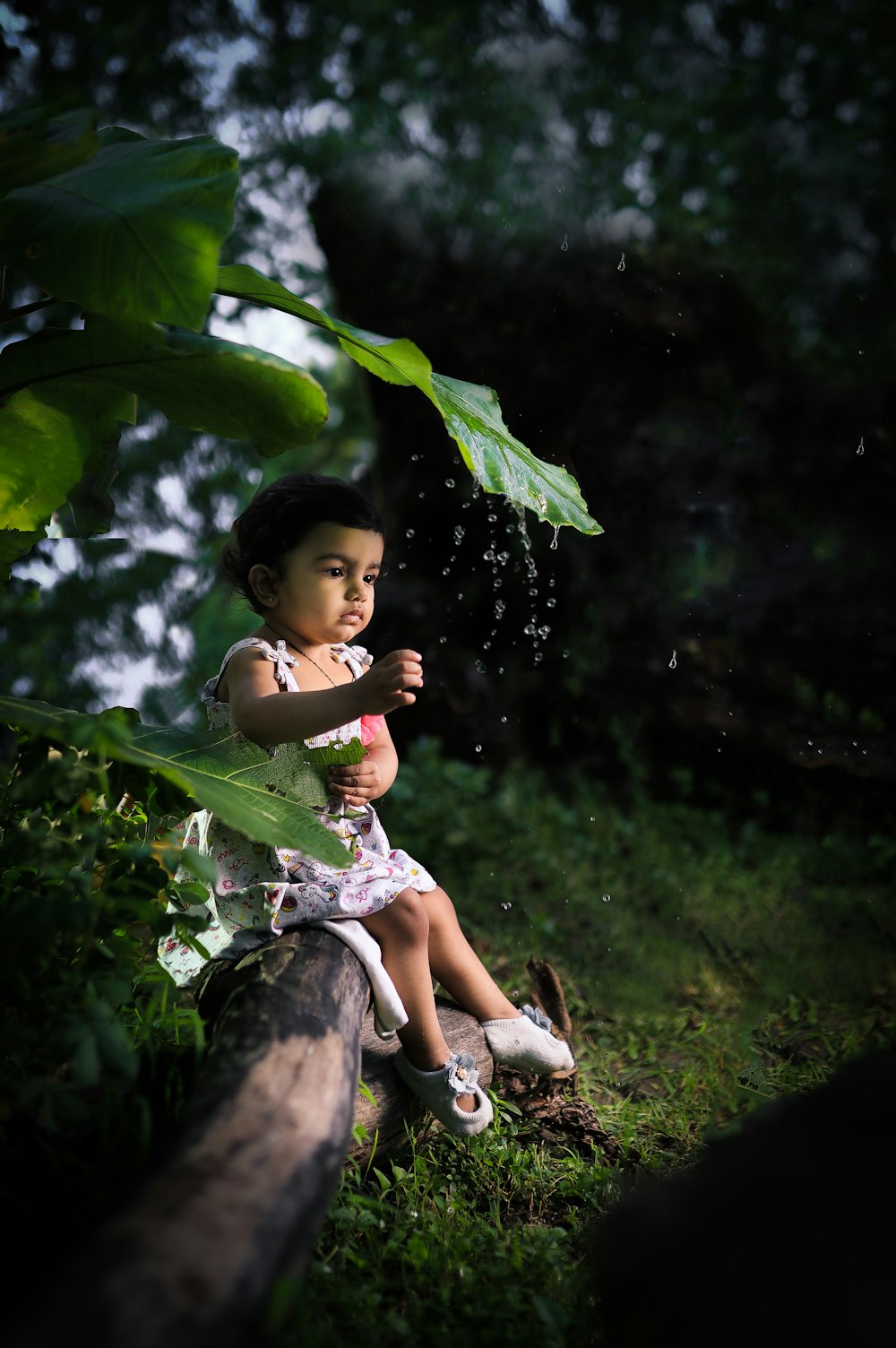 girl in white and green dress sitting on tree branch during daytime