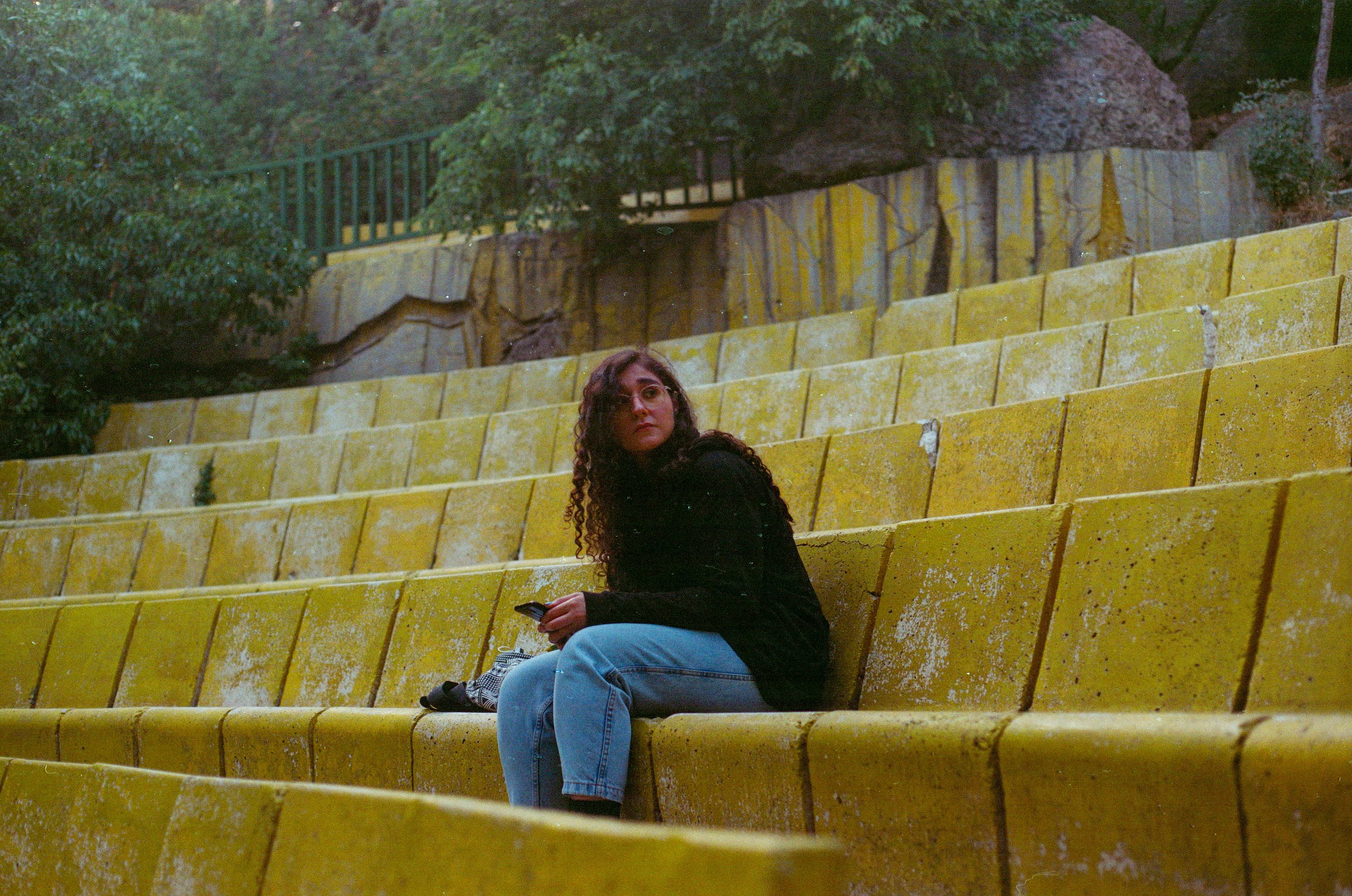 woman in black long sleeve shirt and blue denim jeans sitting on brown concrete stairs
