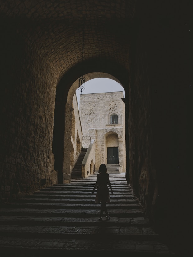 A girl walking in a tunnel during daytime in Naples, Italy. With the shadow we don't see her face.