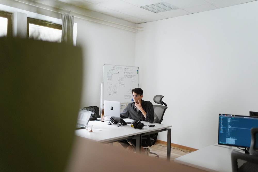 homme en costume noir assis sur une chaise roulante de bureau noire