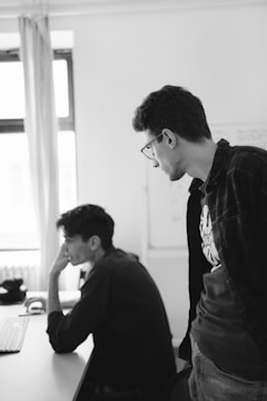 A mentor guiding a young professional through a project on a computer.