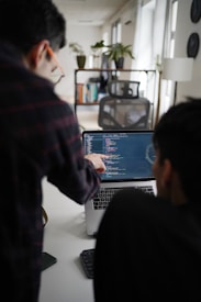 man in black and red plaid shirt using black and gray laptop computer