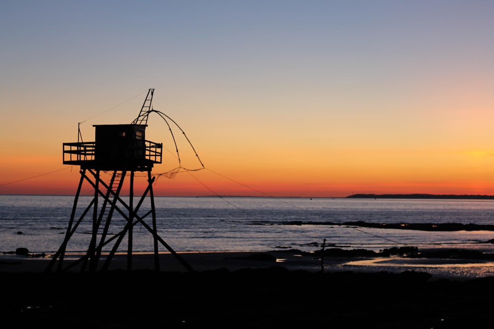 silhouette of lifeguard tower on beach during sunset
