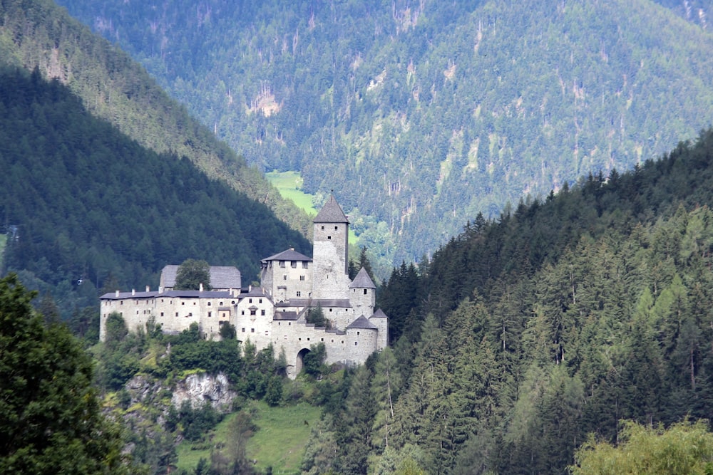 white concrete castle on top of green mountain during daytime