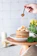 Close-up of a glass jar filled with golden handcrafted syrup drizzling over pancakes.