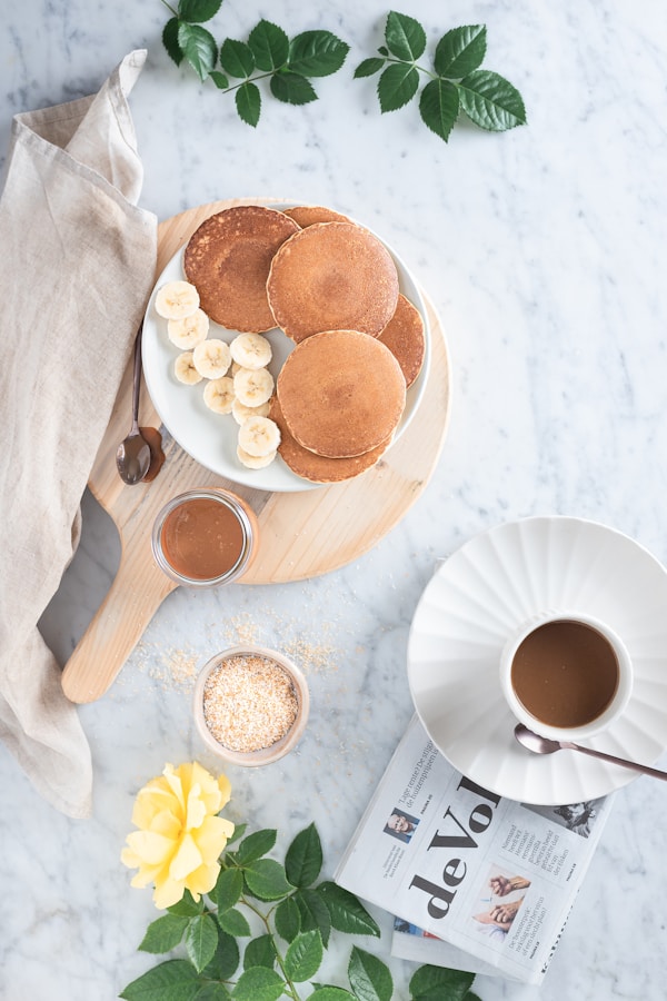White ceramic mug with coffee beside brown cookies on brown wooden tray