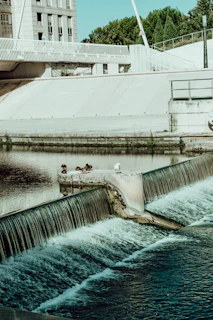 man in white t-shirt and black pants sitting on concrete bridge during daytime