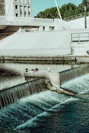 man in white t-shirt and black pants sitting on concrete bridge during daytime