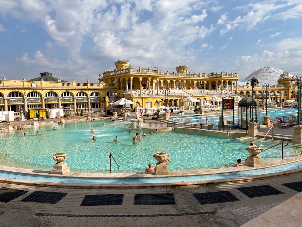 people swimming in pool near building during daytime