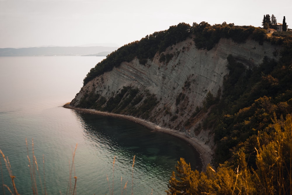 gray rocky mountain beside body of water during daytime