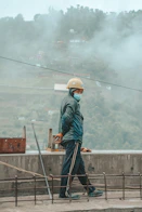 man in blue jacket and white helmet standing on brown wooden dock during daytime