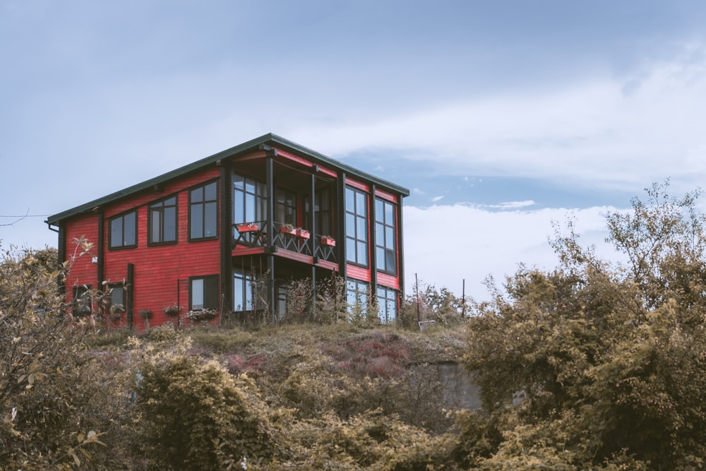 Casa de madera roja y negra rodeada de árboles verdes bajo el cielo azul durante el día