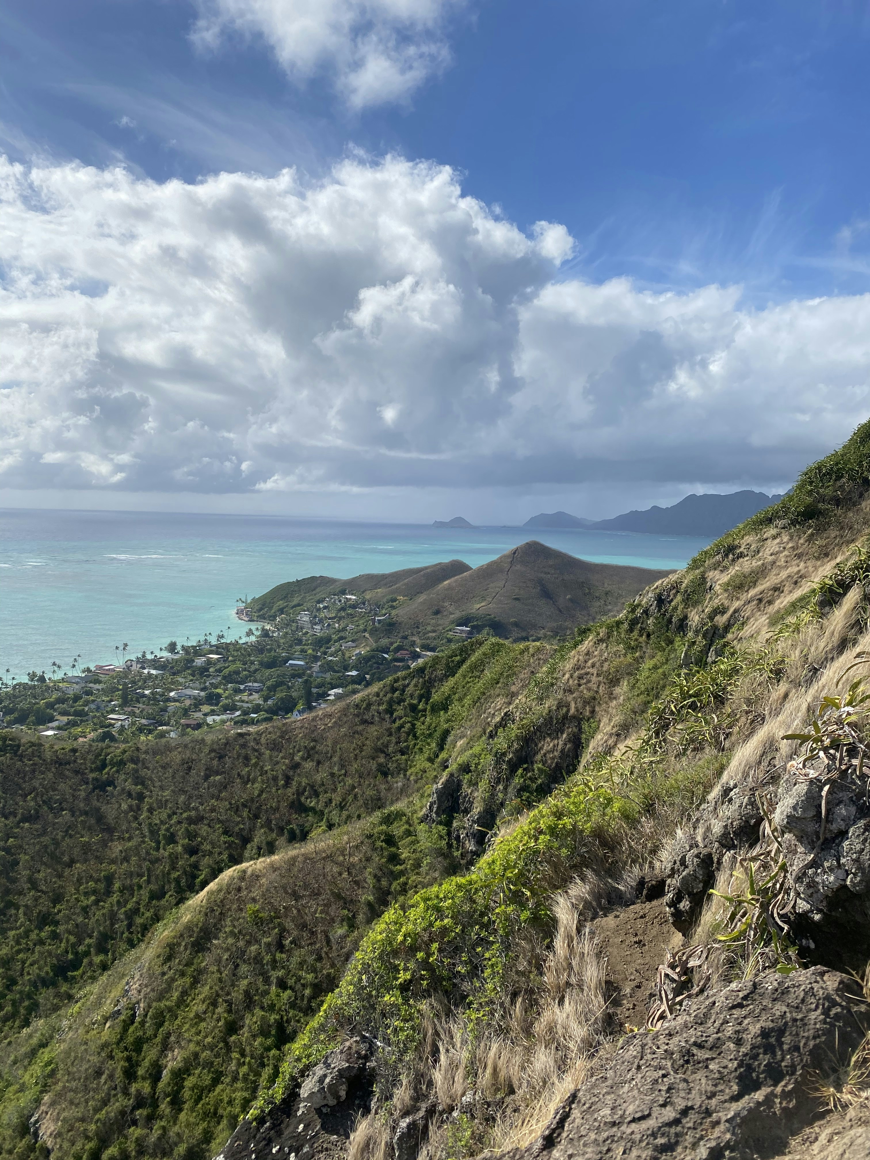 green and brown mountain beside sea under white clouds and blue sky during daytime
