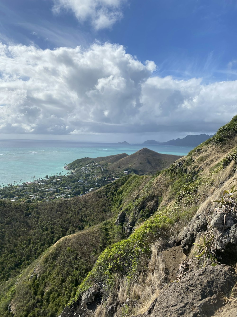 green and brown mountain beside sea under white clouds and blue sky during daytime