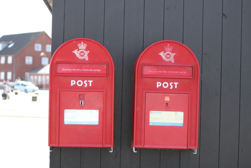Boîte aux lettres rouge sur mur en bois noir