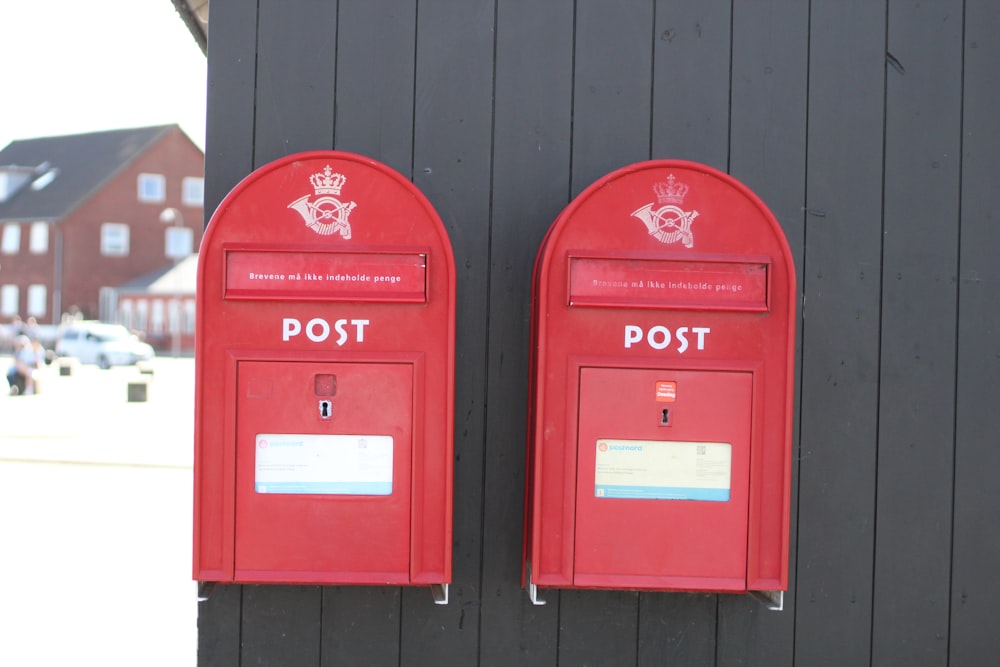 red mail box on black wooden wall