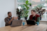 man in red and black crew neck t-shirt using silver macbook