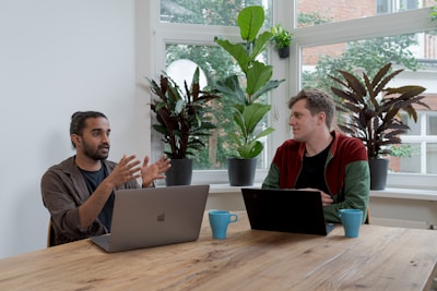 man in red and black crew neck t-shirt using silver macbook