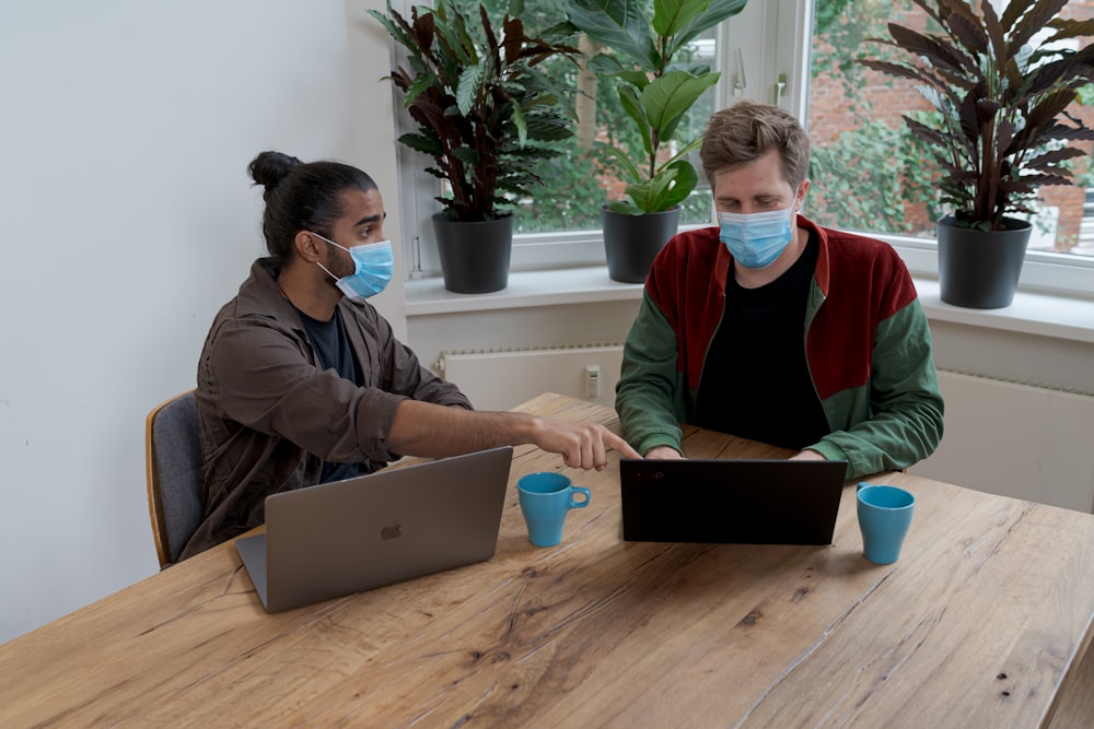 man and woman sitting at table using macbook