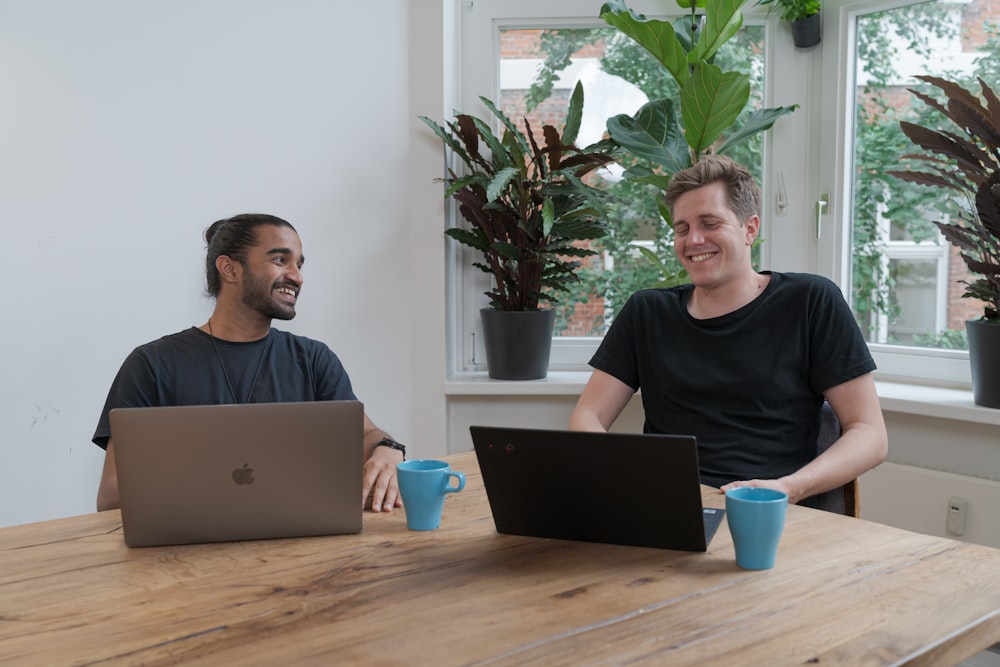 man in black crew neck shirt sitting beside brown wooden table