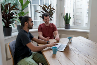 A recruiter and candidate smiling during a consultation, with paperwork and laptops on the table.
