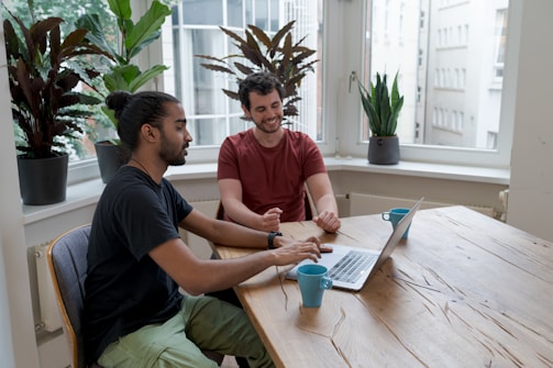 A friendly business consultant discussing plans with a client over a laptop in a cozy office.