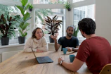 Casual team discussion with coffee cups and greenery, reflecting a warm creative atmosphere.