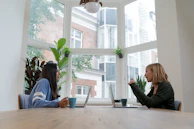 Two professionals exchanging ideas over coffee in an office courtyard full of native plants.