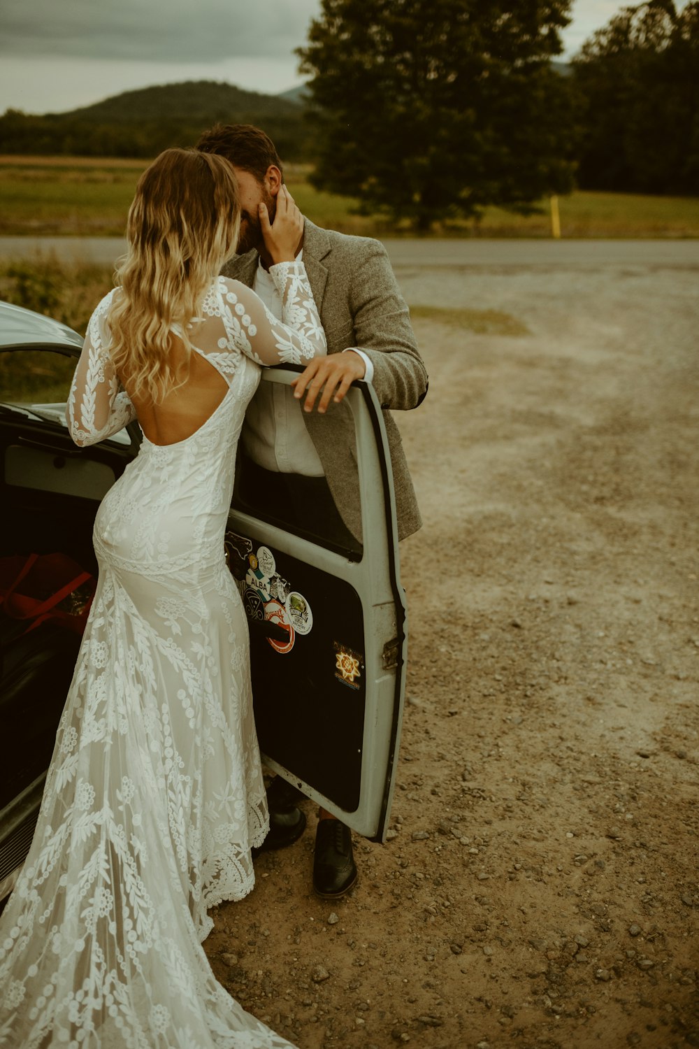 woman in white dress and gray blazer standing beside black car during daytime