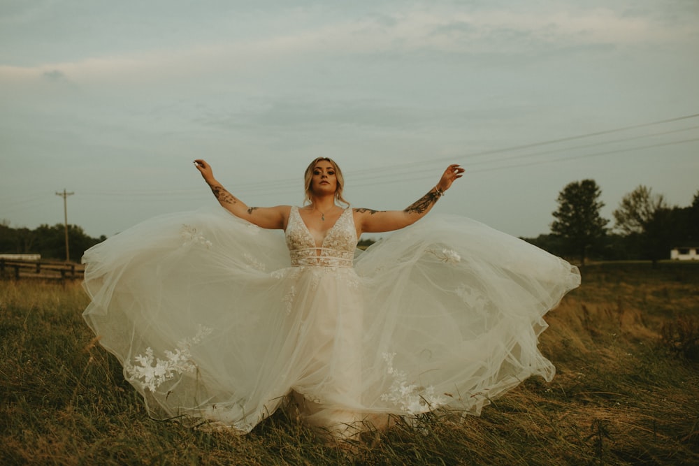 woman in white wedding dress standing on green grass field during daytime