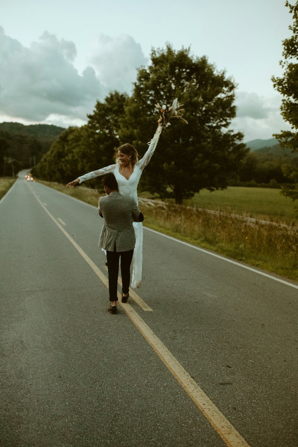 man in white t-shirt and gray shorts standing on gray asphalt road during daytime