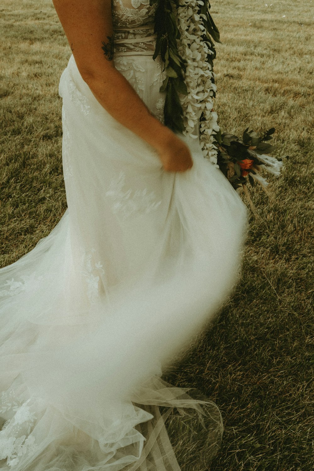 woman in white wedding dress standing on green grass field during daytime